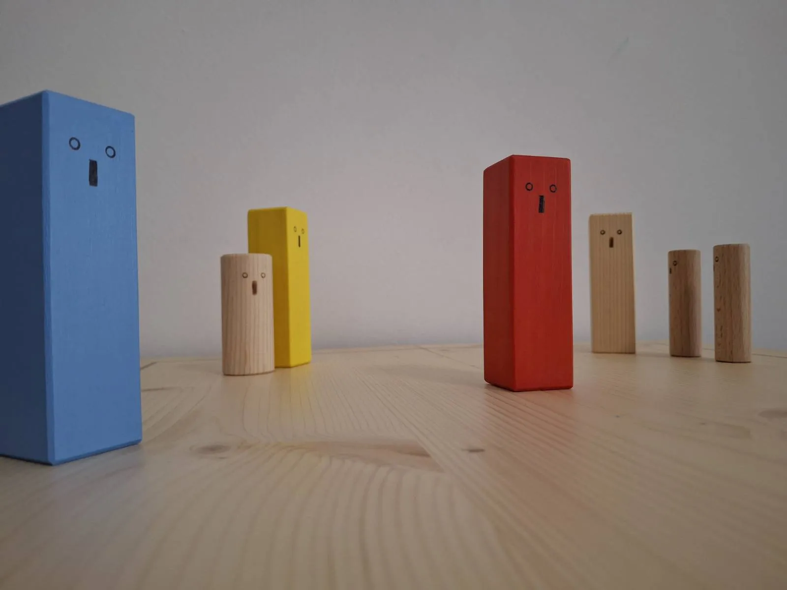Holzbrett mit verschiedenfarbigen Holzfiguren. Figuren sehen in unterschiedliche Richtungen.