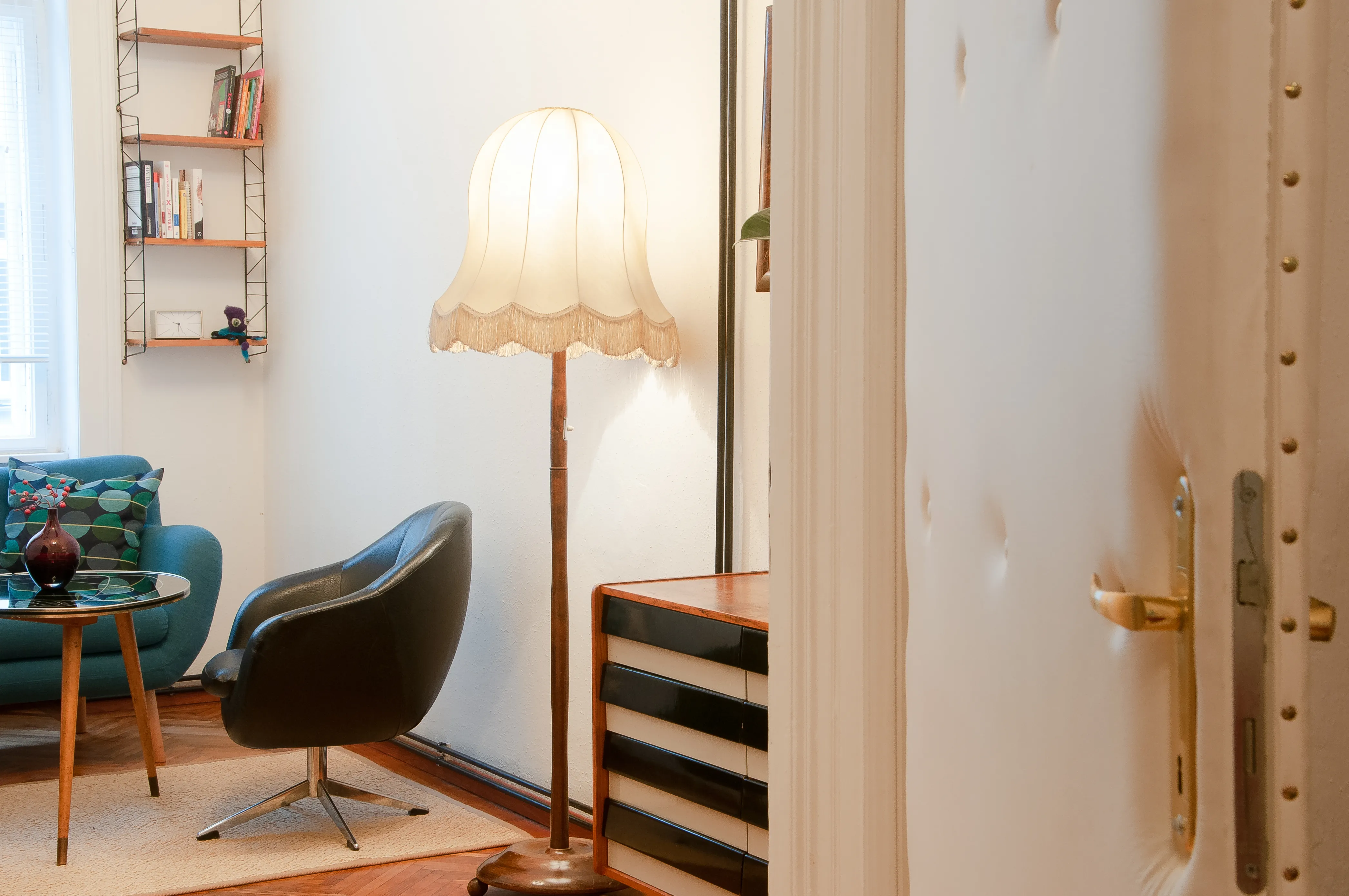Der Blick fällt durch eine Tür in den Therapieraum. Im Raum stehen ein Stuhl und eine Bank an einem Glastisch.